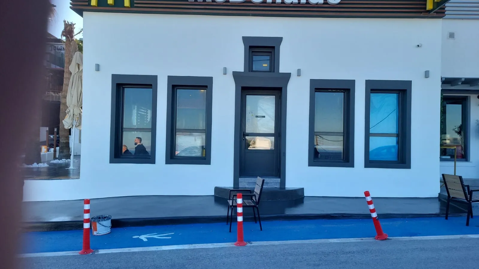 Ανακαινισμένη πρόσοψη McDonald's με λευκό σοβά και σκούρα γκρι κουφώματα